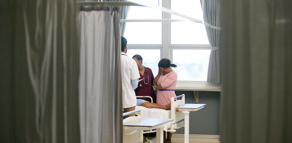 Grieving woman by the side of a hospital bed Grieving woman by the side of a hospital bed